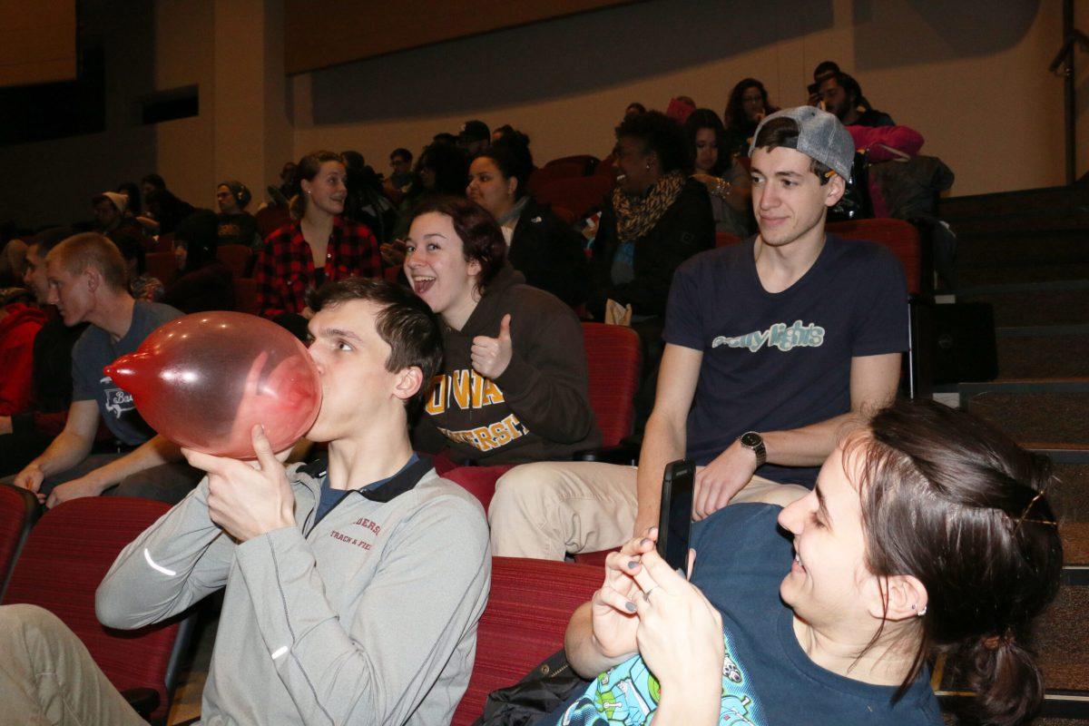 Students look on as Charlie Grab blows up a condom during Sex Toy Bingo on Feb. 17. The event welcomed more than 500 students, and featured games like “Guess the Lube Flavor,” in addition to traditional bingo. -Photo Editor/Justin Fata