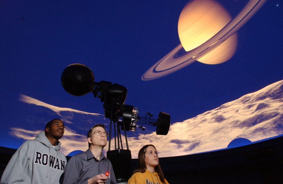 Former planetarium director Keith Johnson stands with students inside the Edelman planetarium. -Photo courtesy of Rowan University, provided by Keith Johnson