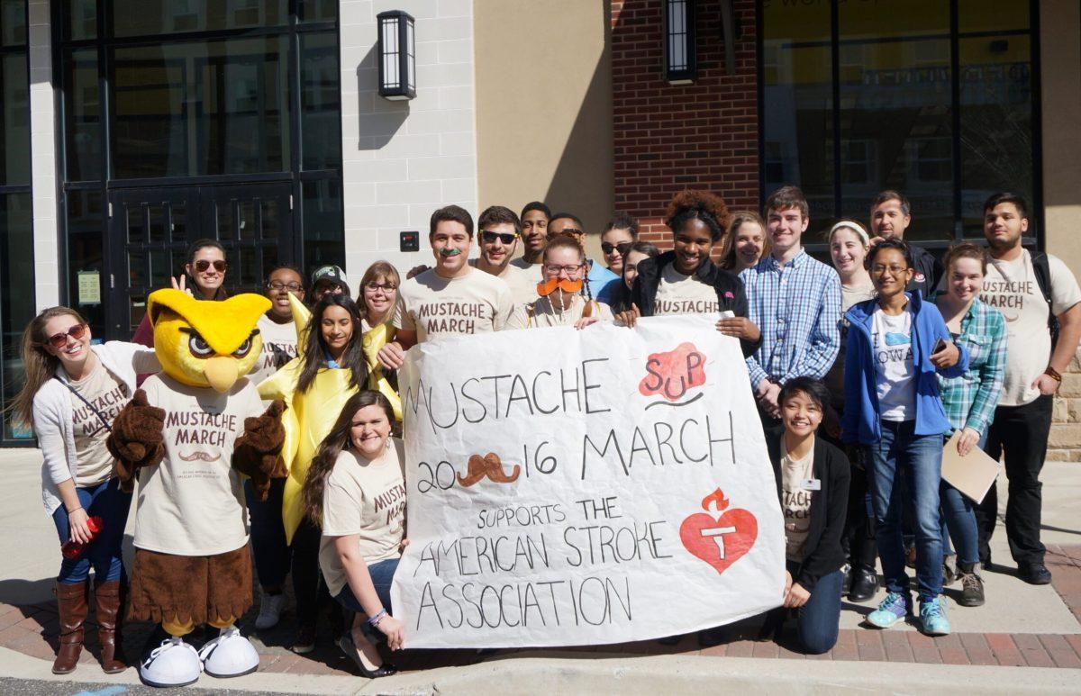 Students and Faculty gather together for a photo as they march down Rowan Blvd. for Mustache March, which supports the American Stroke Association on February 29, 2016. (Anthony Medina | Staff Photographer)