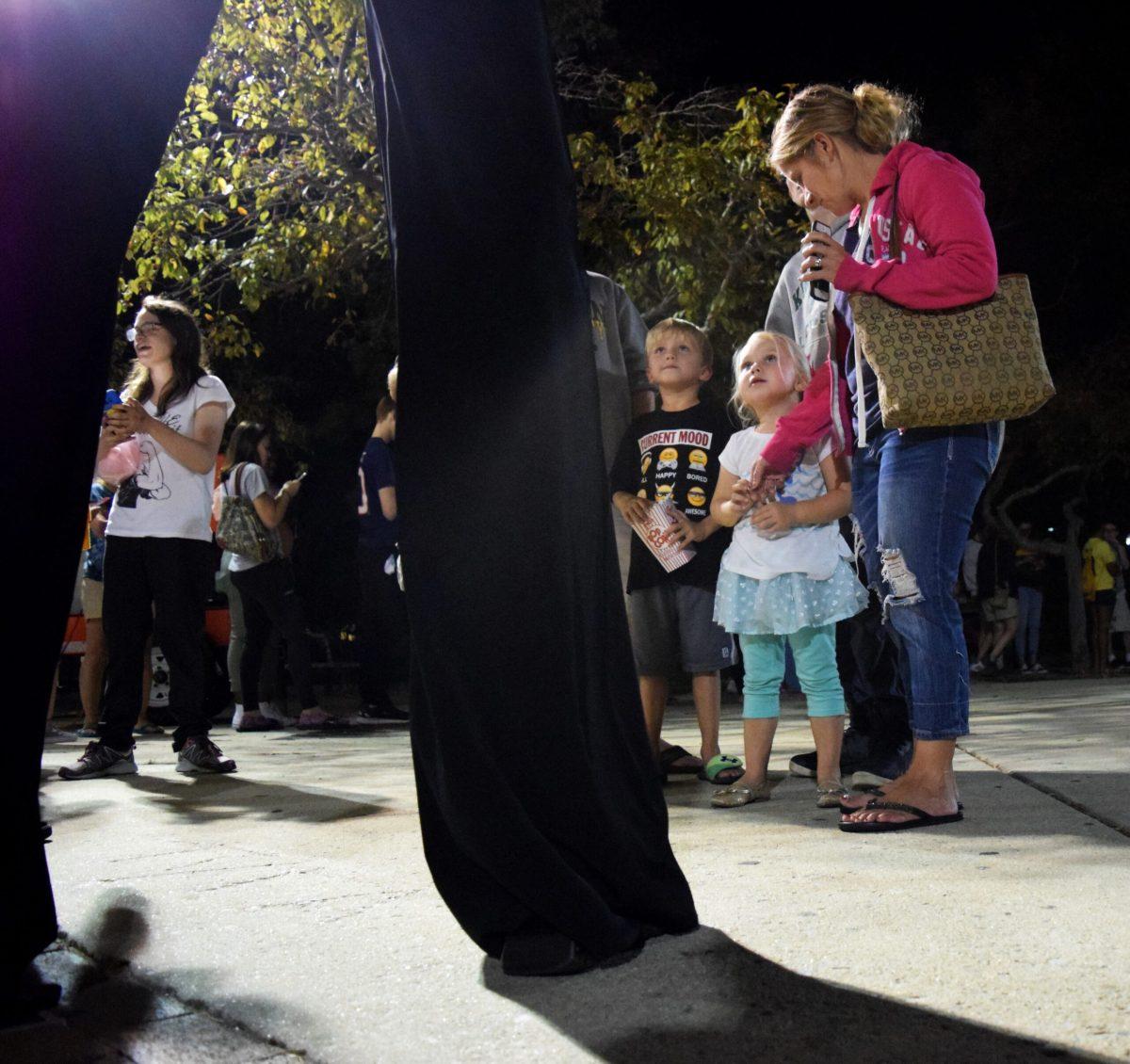 Aiden and Hailey Bussey (left to right) look up at a man on stilts. -Staff Photo/Andrew Turco