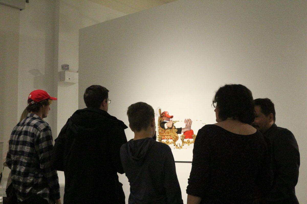 Attendees looking at a piece titled "Active Shooter." -Staff Photo/Maria Morales