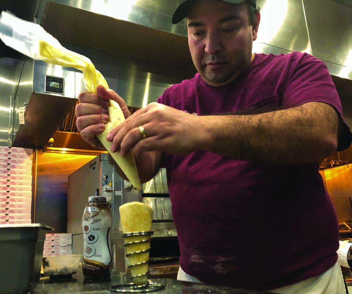 Henry Fernandez, owner of Cono Pizza & Ice Cream makes cannoli cone. -Staff Photo/Justin Decker