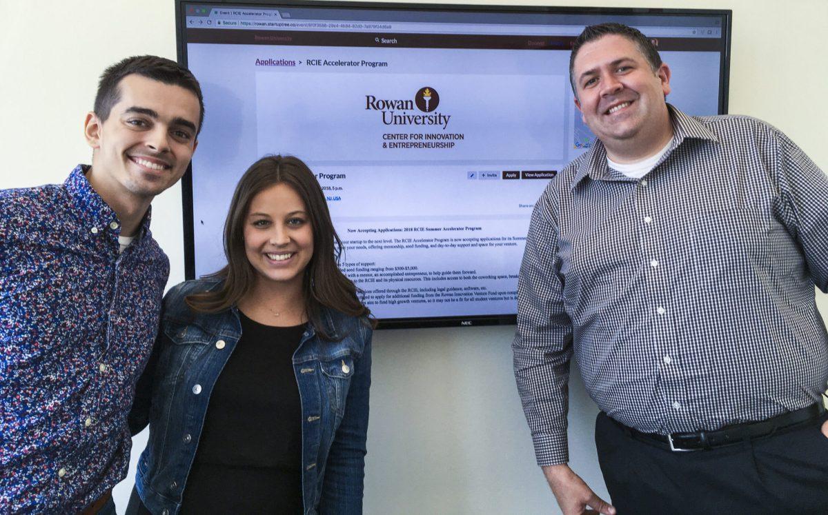 (L to R) Dylan Grana, Jessica Wolk and Eric Liguori pose in front of the homepage for the Rowan Accelerator Program. -News Editor/Matt Kass