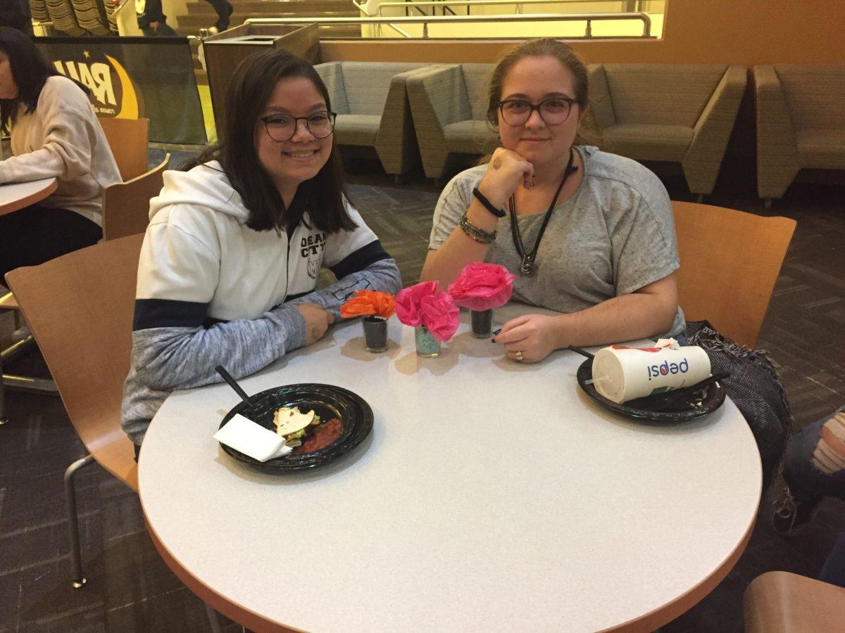 Sophomores Angela Gaudio and Caitlin Maurer construct paper marigolds at the craft table. - Contributor/Sanjana Kondapalli