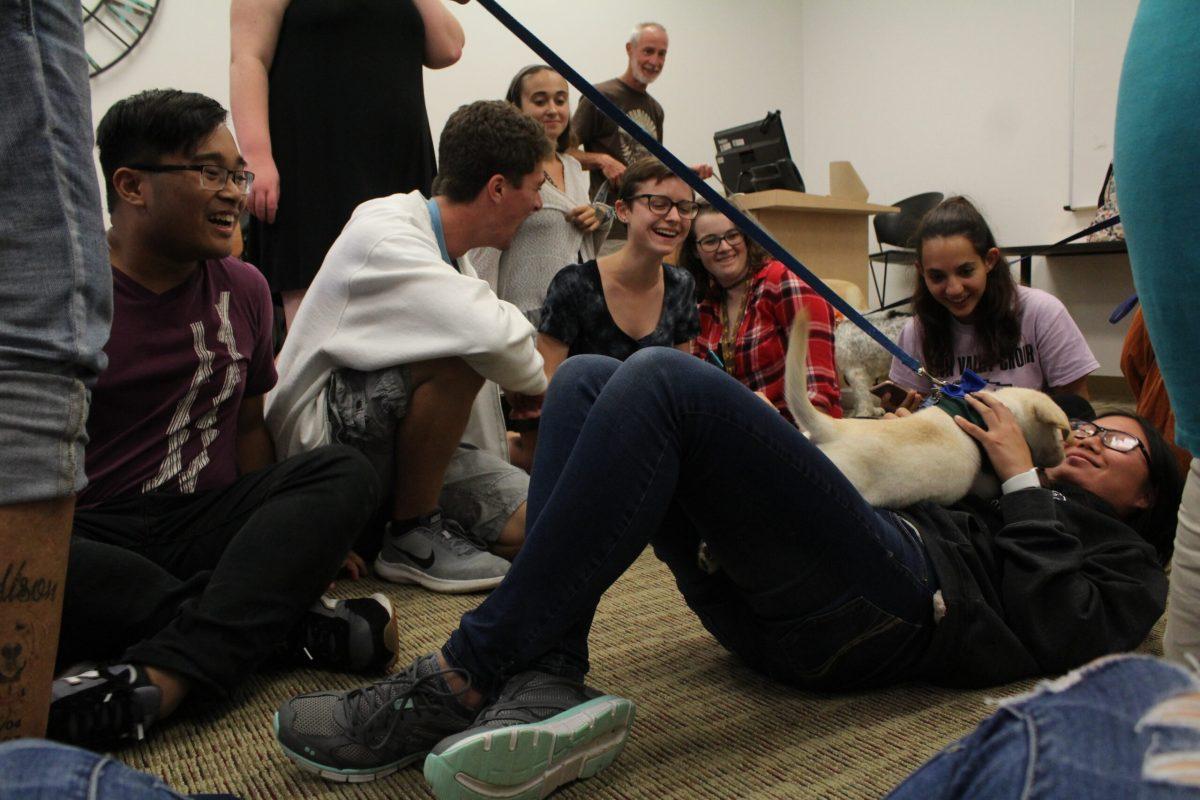 Students playing with a puppy at a Paws for a Break event. -Photo/Amanda Palma