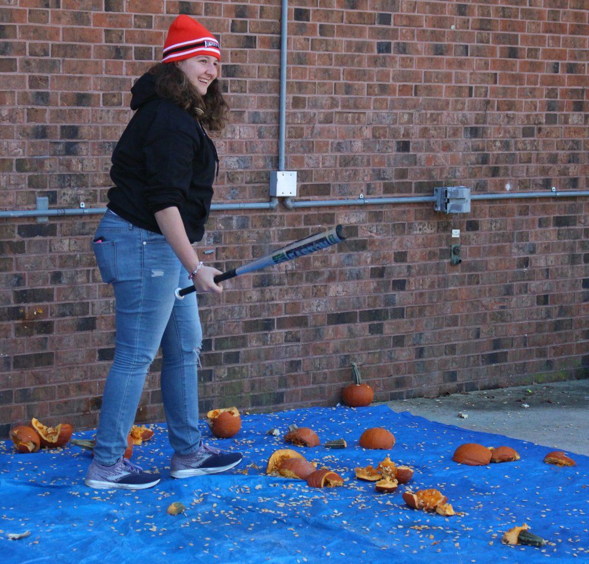 Jessica Haya, a sophomore engineering entrepreneur major, smiles after hitting a pumpkin with a bat. Haya participated in the Pumpkin SMASH to help generate donations for the SHOP. - Staff Writer / Kristin Guglietti