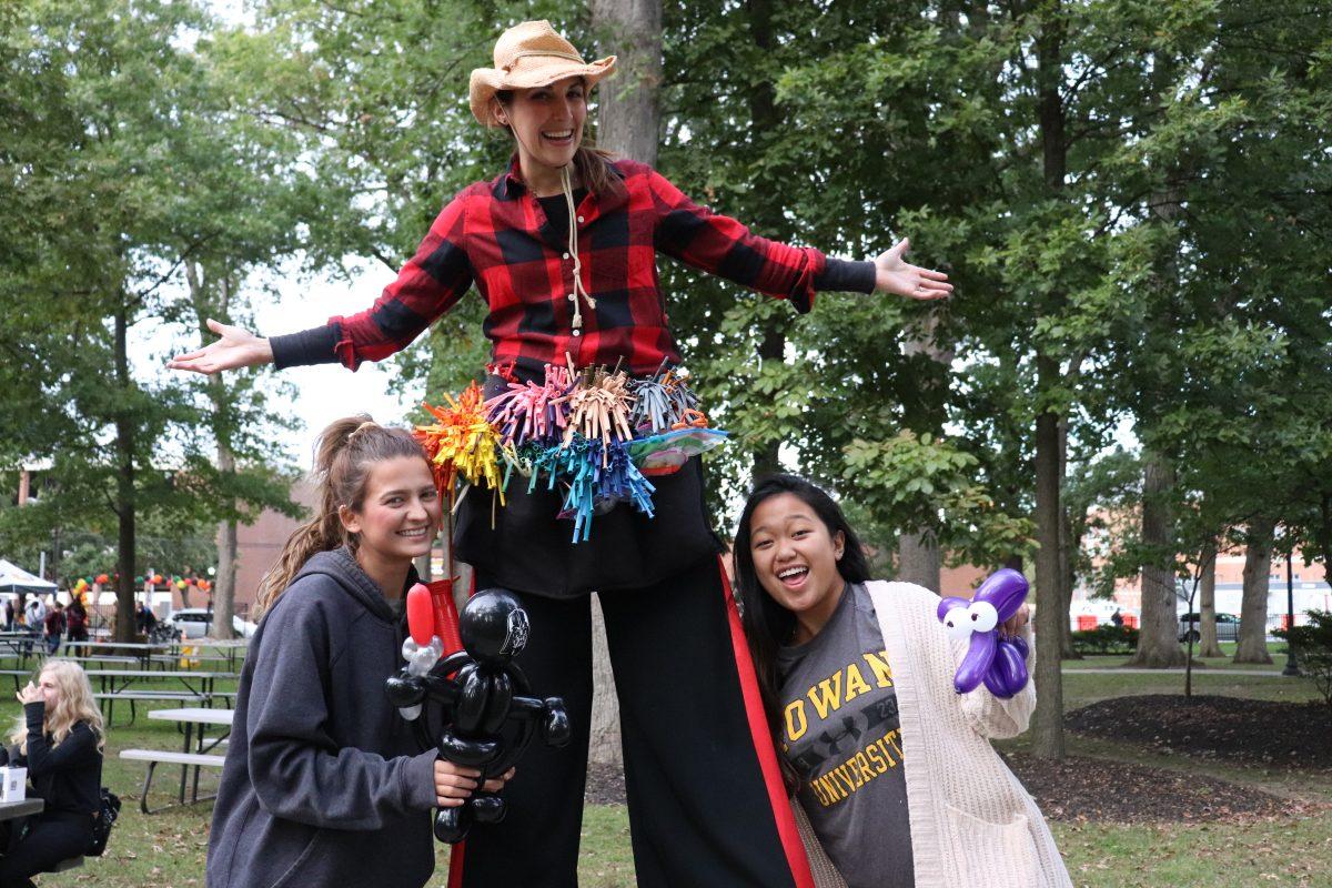 Two students pose with their newly-created balloon creatures and the balloon artist who made them. This was just one of the various activities for students and alumni at the homecoming Harvest Festival. - Multimedia Editor / Dyone Payne