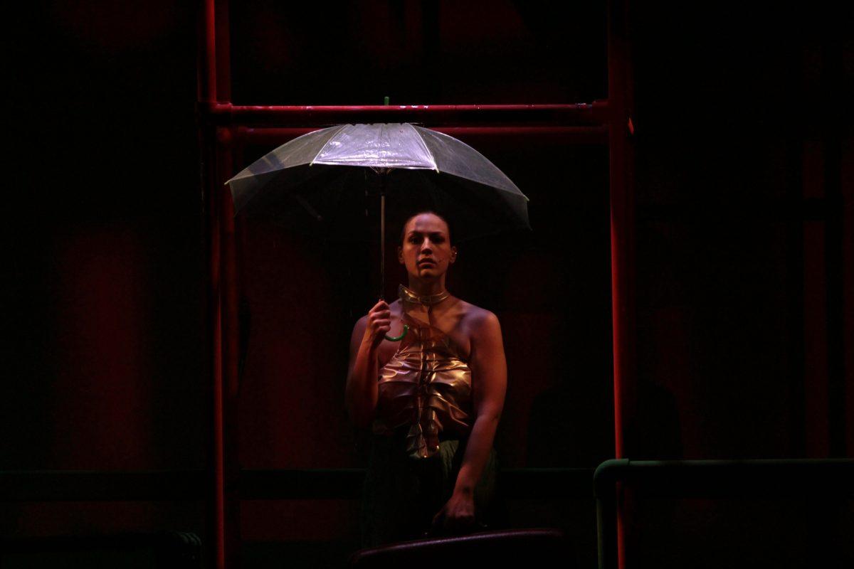 Eurydice, played by Kayla Bowe, shields herself from the rain as she enters the underworld. /  Kristin Guglietti
