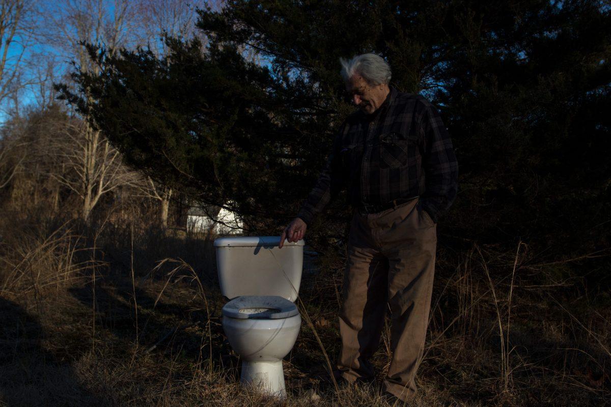 Robert P. Tucker, a Glassboro State alum, posing in front of one of the 13 toilets in his "sculpture garden." - Multimedia Editor / Alex Rossen