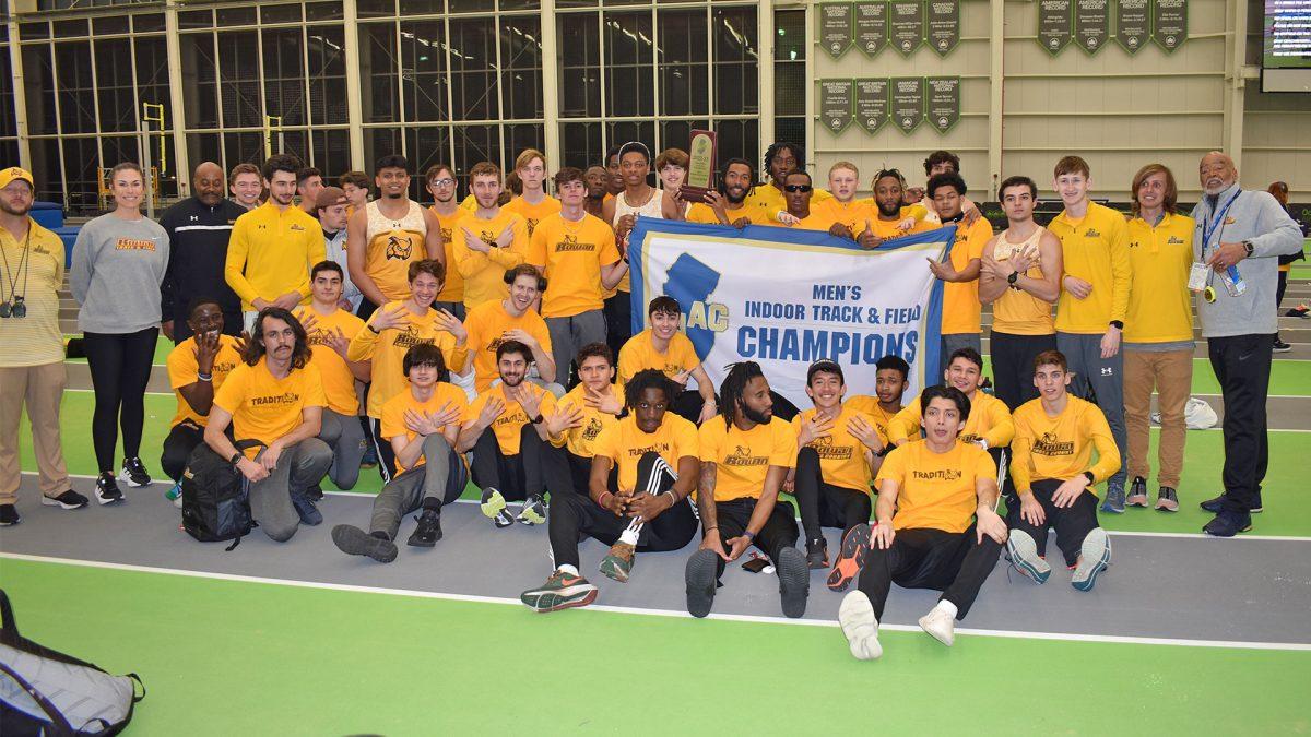 Rowan men's indoor track & field team posing with their championship banner. This was their eighth championship in a row. - Photo / Rowan Athletics 