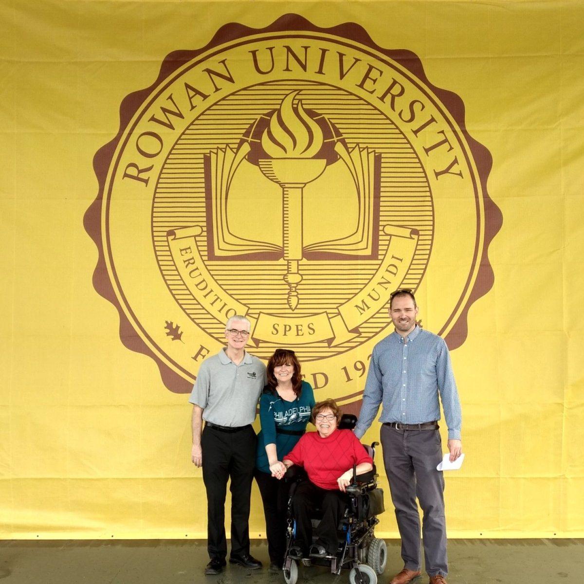 Judy Heumann and others pose in front of the Rowan seal before she spoke at the 2019 Rowan Commencement. - Photo via @judithheumann on Twitter