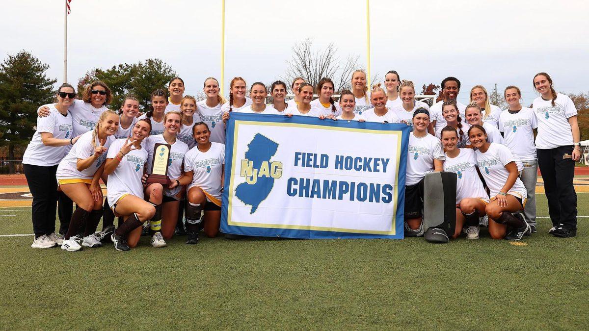 The team holds up their championship banner. Rowan won its third straight NJAC title this past Saturday. - Photo via Rowan Athletics