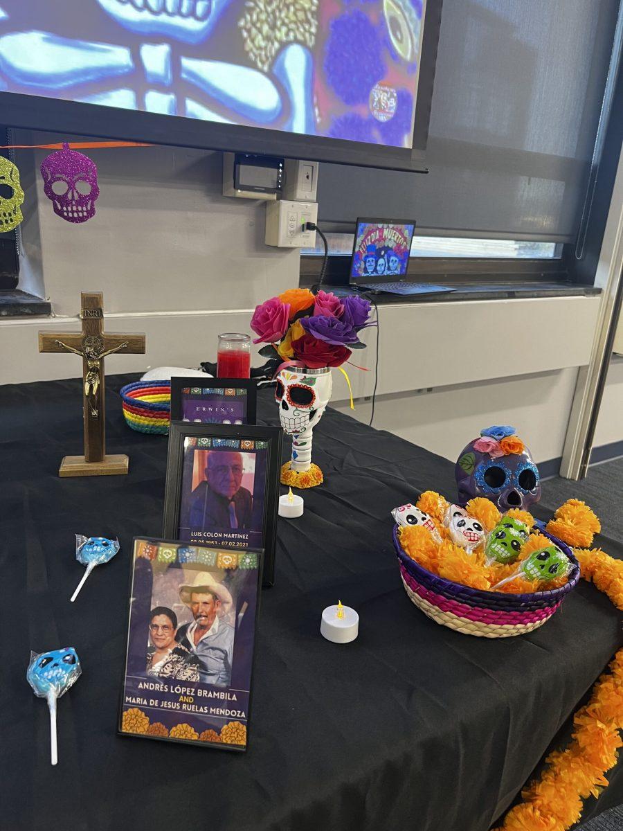 The communal altar with offrendas including photos, flowers, and candy. - Staff Writer / Isaac Linsk