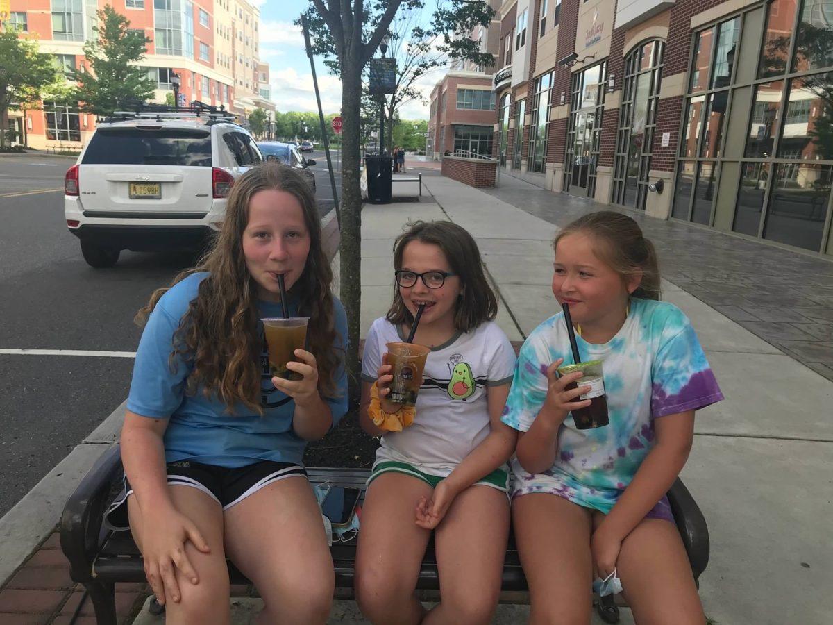 From left to right, Shockey, her younger sister Grace, and her cousin Maura sit on Rowan Boulevard enjoying their drinks from Kung Fu Tea on Jun. 7, 2020. - Photo via Sarah Shockey