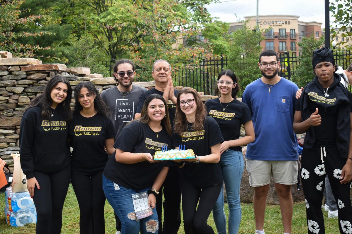 Rowan Arabic Culture Club E-board members pose for a photo during the food festival outside Discovery Hall. President Maryam Mady and Vice President Sarah Huber hold a cake for their birthday. - Staff Photographer / Owen Miller