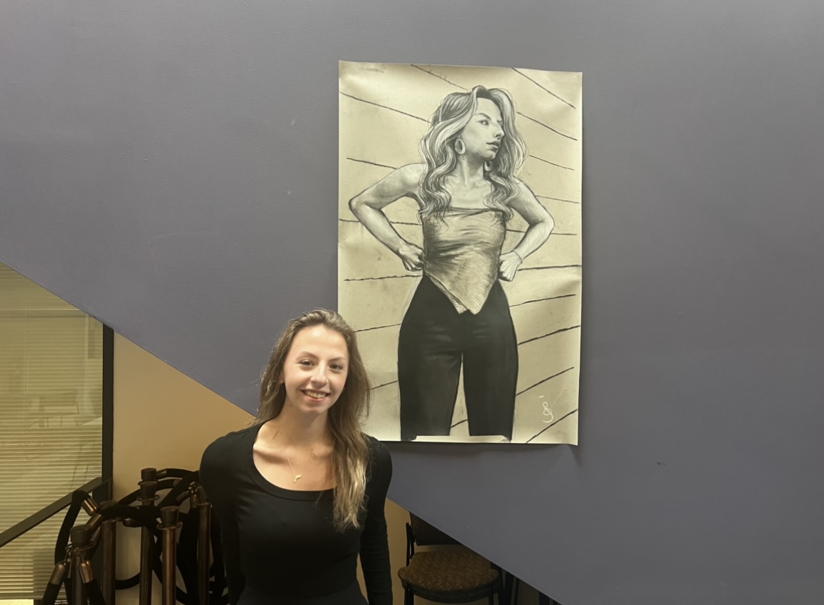 Chloe Ditzel standing with her self portrait in Savitz Hall. - Arts & Entertainment Editor / Beth Cimaglia