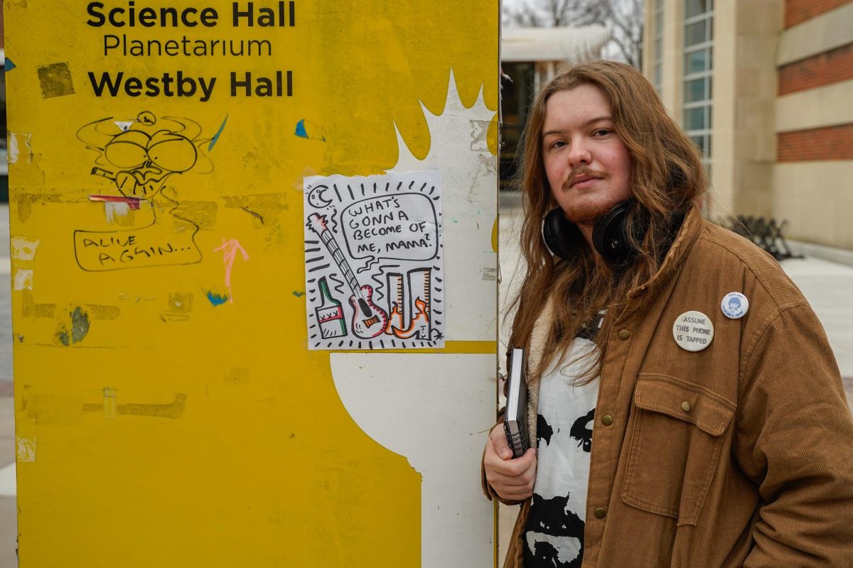 Joseph Worosila (Joe Warr) poses for a photo next to two works of his art outside of the library. Glassboro, NJ. Saturday, Feb. 8, 2025. - Photography Editor / Gavin Schweiger