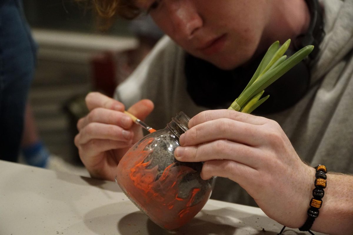 Jackson Hesley paints flames on his potted plant from the Paint and Plant Event at 230 Victoria. Glassboro, NJ. Tuesday, Mar. 11, 2025. - Staff Photographer / Truman Steffen