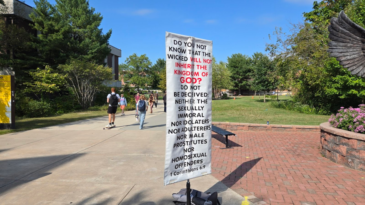 A sign held up by Roy Nembhard in front of the Rowan Owl statue. (Aidan Vanhoof). 