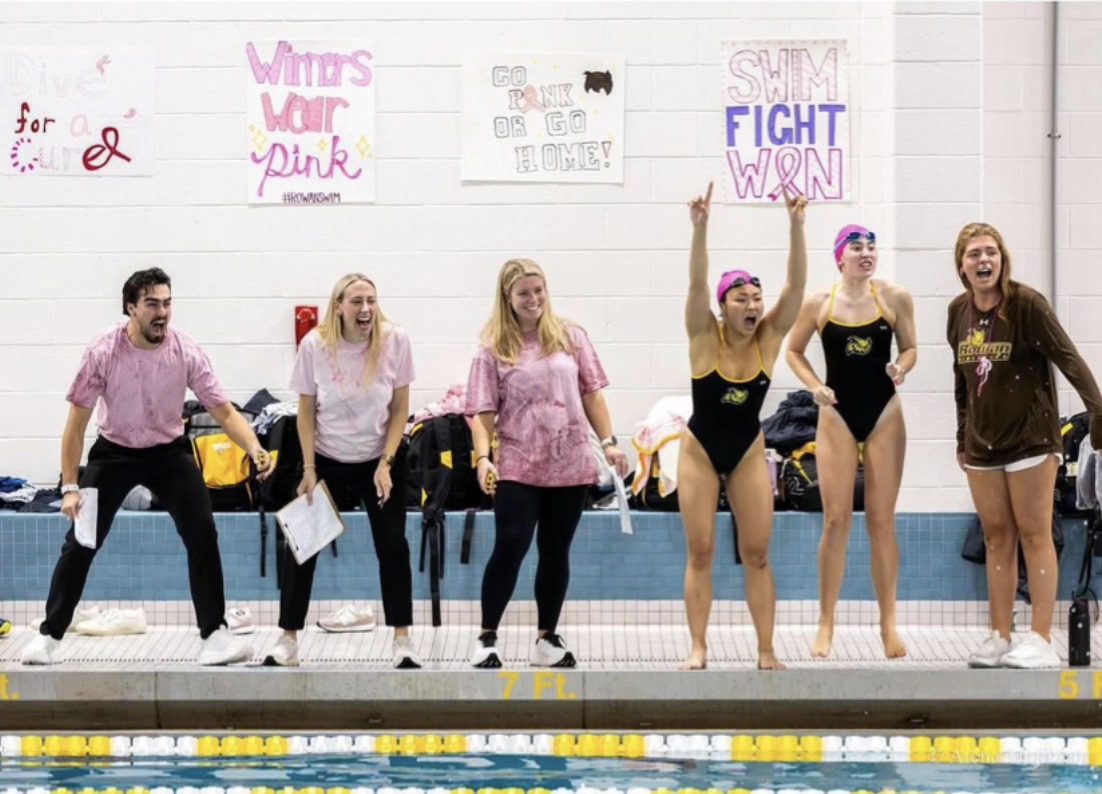 Gerardo Gonzalez Ruiz (left) cheers on a swimmer poolside. (Rowan Athletics)